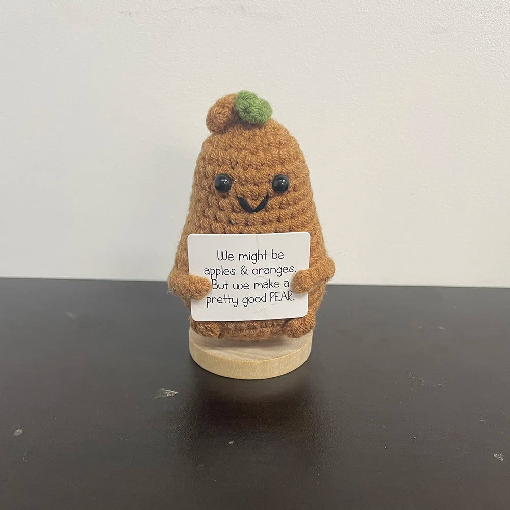 Handmade crochet pear doll holding a sign that says "We might be apples & oranges, but we make a pretty good PEAR